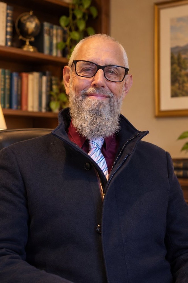Shaun T. Richards, linguist and AI evaluator, smiling in a warmly lit study.